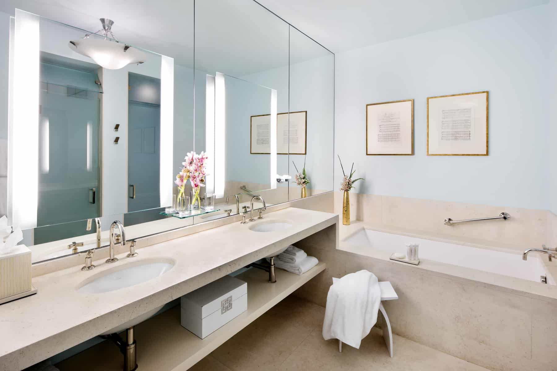 Wide Shot of the bathroom inside Suite Two of the Ivy Baltimore. By the bathtub, a towel is laid over a simple footstool.