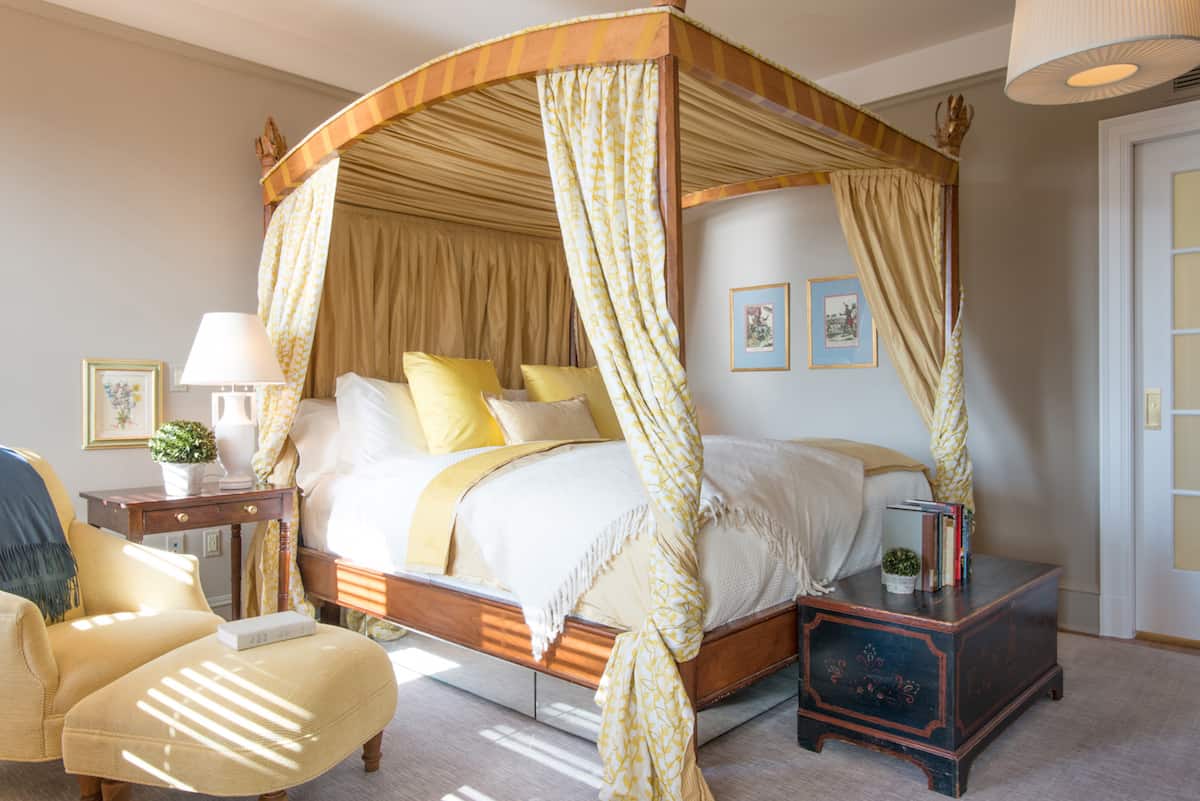 Bedroom of Suite Fourteen, inside the Ivy Hotel Baltimore. Sunlight is cast on this top side accomodation, giving extra vibrance to the gold hues of the four poster bed.